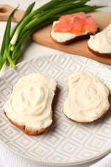 Plate of tasty sandwiches with cream cheese on light background