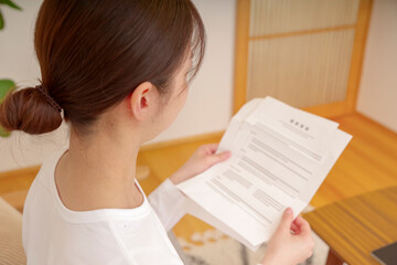 リビングで書類を見つめる女性