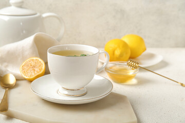 Teapot with cup of fresh mint tea, lemons and honey on grunge light table