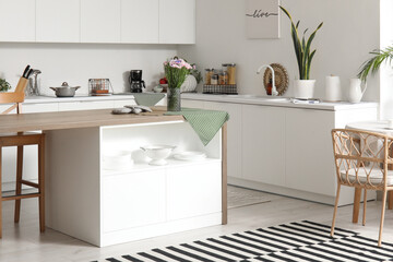 Interior of modern kitchen with white counters and island table