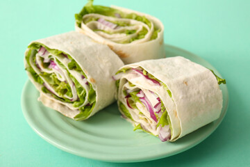 Plate of tasty lavash rolls with onion and greens on turquoise background