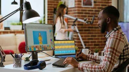 African american photo editor retouches images on his computer in a tech inspired workspace. Man...