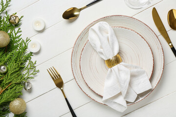 Beautiful table setting with Christmas balls, coniferous branches and burning candles on white...