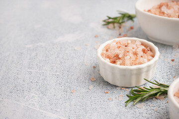 Bowls with Himalayan pink salt and rosemary on white background