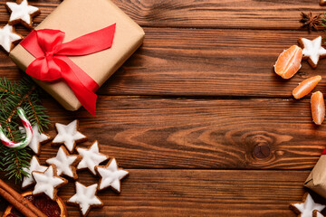 Composition with delicious stars shaped Christmas cookies, gift box, mandarin and fir tree branch on wooden background