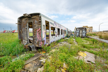 Fototapeta premium Destroyed, dilapidated and abandoned passenger train carriages next to the disused railway station in the city of Barreiro-Portugal.