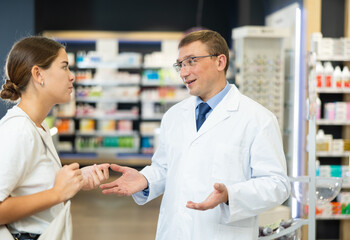 Obraz premium Male pharmacist and young female customer having conversation in a pharmacy