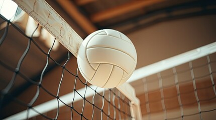 A volleyball is suspended above the net inside an indoor sports facility capturing the intensity and excitement of a competitive match in progress