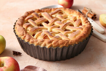 Baking dish with tasty homemade apple pie and fruits on beige grunge background