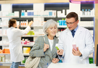 Obraz premium Elderly woman client consults with a pharmacist which medicinal ointment to buy