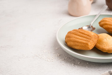 Plate with delicious madeleines on light background