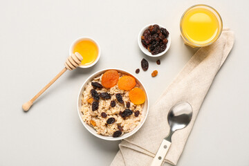 Tasty oatmeal with dried fruit on light background