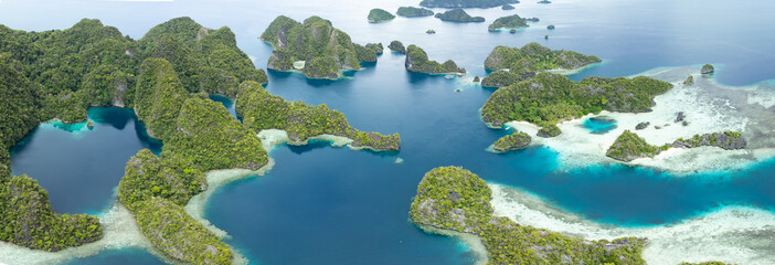 Rugged limestone islands rise from the seascape in Misool, Raja Ampat, Indonesia. This area is known as the heart of marine biodiversity and is a popular destination for diving and snorkeling. © ead72