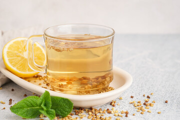Glass cup of fresh buckwheat tea, mint and lemon on light background, closeup