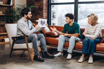 Male doctor explaining medical test results to teenage patient and his mother