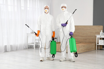 Male workers with disinfectant in bedroom