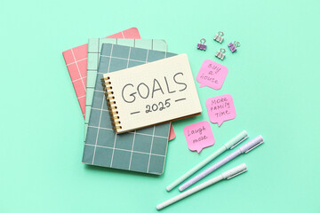 Notebooks with to do list, sticky notes and stationery on cyan background. New year goals concept