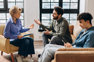 Emotional father talking with psychotherapist about his son at therapy session