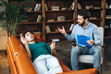 Male psychoanalyst gesturing during meeting with teenage boy in the office
