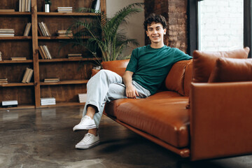 Happy teenage boy with braces sitting on couch in psychoanalyst office