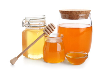 Jars and bowl of sweet honey with dipper on white background