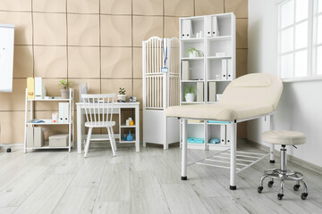 Interior of medical office with couch, doctor's workplace and shelf units