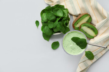 Glass of fresh spinach smoothie with kiwi on grey background