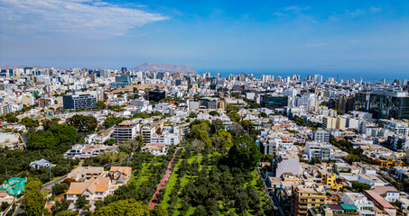 Fototapeta premium Urban aerial view of San Isidro, Lima, with visible sea in the background and El Olivar park in the front.