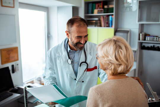 Smiling senior doctor talking to female patient during medical consultation in clinic
