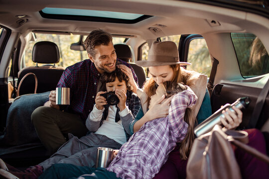 Family road trip fun with kids playing and taking photos in the car trunk