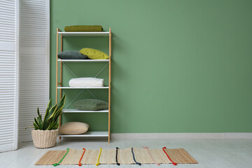 Interior of stylish room with pillows, shelving unit and houseplant