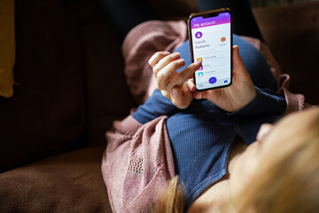 Pregnant woman using mobile banking app while relaxing on couch