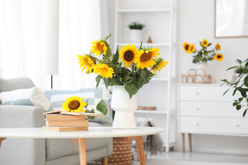 Vase with sunflowers and books on table in light living room