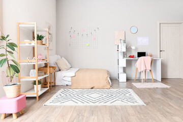 Interior of light teenager's room with bed, shelf unit and study table