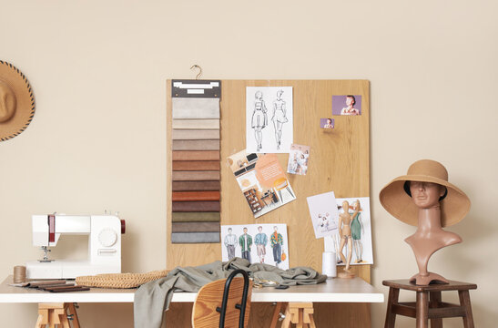 Interior of stylish atelier with tailor's workspace, sewing machine and mood board