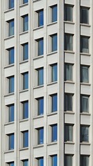 Fototapeta premium Modern building facade with numerous windows reflecting the sky. A geometric pattern of rectangular windows creates a striking visual. Ideal for architecture, design, and urban themes.