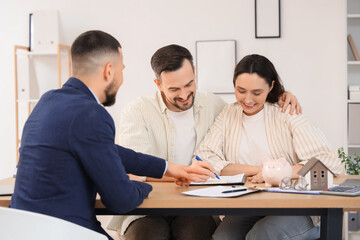 Young couple with real estate agent filling out house rental agreement in office
