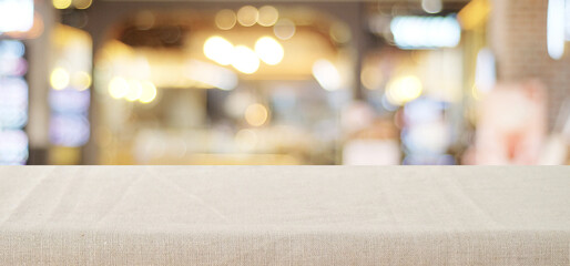Empty table with linen tablecloth over blurred abstract with bokeh background banner, food and product display montage template, backdrop, wallpaper