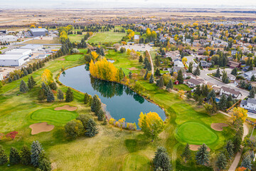 Fototapeta premium Golf course with a pond and a residential area in the background
