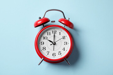 Red alarm clock on light blue background, top view