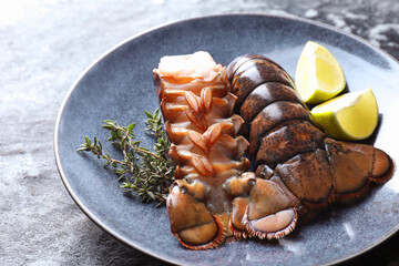 Raw lobster tails, lime and thyme on dark table, closeup