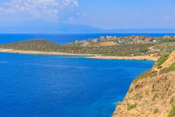 A beautiful blue ocean with a rocky shoreline and a small town in the distance