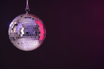 Shiny disco ball on dark purple background, space for text
