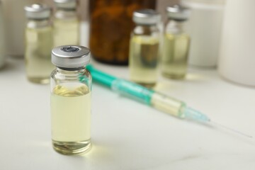 Hepatitis vaccine in glass vials and syringe on white table, closeup. Space for text