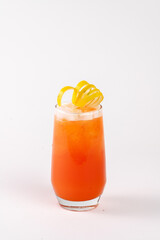 A glass of orange juice with a slice of lemon on top. The glass is half full and the drink is a bright orange color