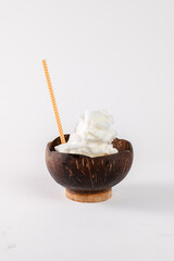 A bowl of ice cream with a straw in it. The bowl is made of wood and the ice cream is white