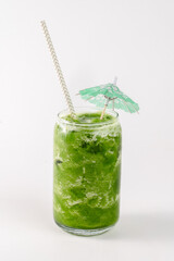 A glass of green juice with a straw and a green umbrella on top. The umbrella is made of straws and is placed on top of the glass