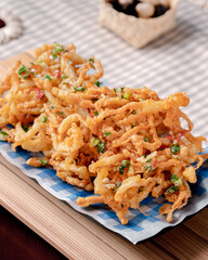 A plate of fried food with a blue and white checkered tablecloth. The food is golden and crispy, and it looks delicious