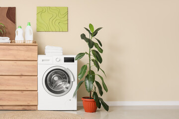 Interior of laundry room with modern washing machine near beige wall