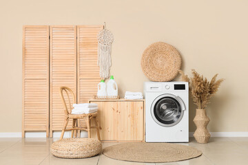 Interior of laundry room with modern washing machine near beige wall